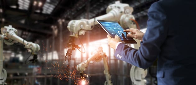 Figura 1: Un ingeniero industrial gerente utiliza un software de sistema de monitoreo en tiempo real para verificar y controlar robots habilitados para 5G en el taller.
